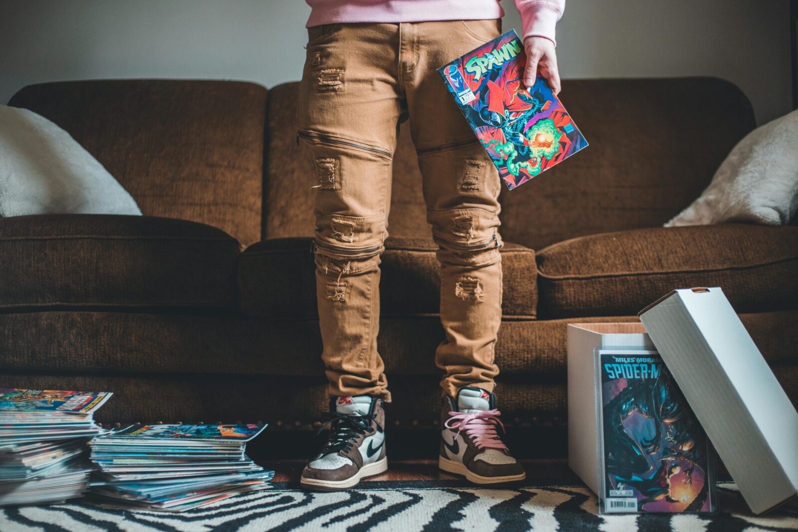 Person holding a comic book in a stylish living room setting.